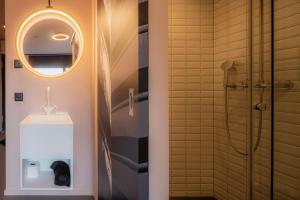 bagno con doccia, lavandino e specchio di BLOOM Boutique Hotel & Lounge Basel a Basilea