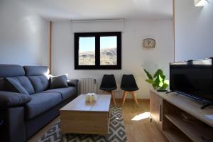a living room with a blue couch and a tv at Lux Aigle "Acceso directo a pistas" in Pas de la Casa