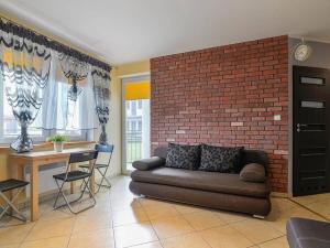 a living room with a couch and a brick wall at APARTAMENT KLAUDIA in Krynica Morska