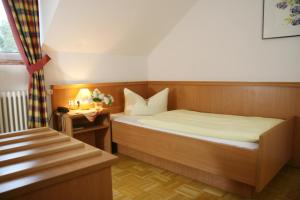 a small bedroom with a bed and a table at Hotel-Gasthof Eberherr in Forstinning