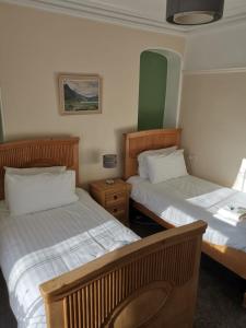 a hotel room with two beds and a lamp at Mairs Bed and Breakfast. in Bridgend