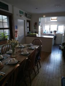 a dining room table with chairs and a kitchen at Mairs Bed and Breakfast. in Bridgend