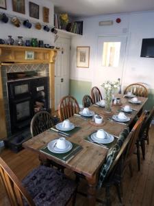 a dining room table with chairs and a wooden table with plates and bowls at Mairs Bed and Breakfast. in Bridgend
