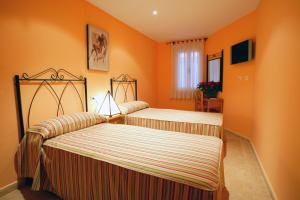 two beds in a room with orange walls at APARTAMENTOS HOTEL 77 in Ayora