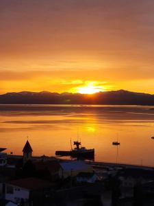 a sunset over a body of water with a boat at LiveUshuaia Beagle View in Ushuaia