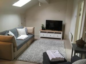 uma sala de estar com um sofá e uma televisão de ecrã plano em Stylish City Centre Flat em Leeds
