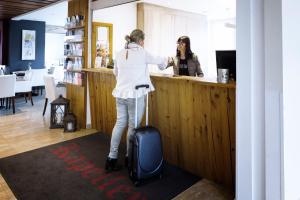 a woman standing at a bar with her luggage at Hotel Kapeller Innsbruck in Innsbruck