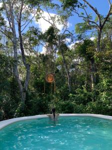 una persona en una piscina con un reloj de fondo en Casa Tzalam Tulum selva, en Tulum