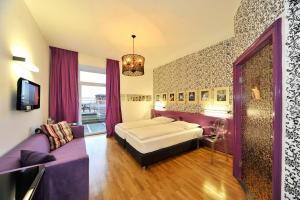 a bedroom with a bed and a purple couch at Erlebnis Post - Stadthotel mit EigenART in Spittal an der Drau