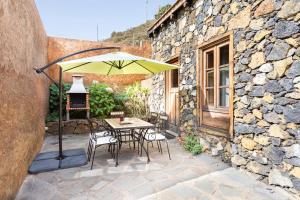 una mesa y sillas con una sombrilla en el patio en Casa Rural La Pestilla 1, en El Pinar de El Hierro