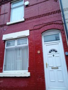un edificio de ladrillo rojo con una puerta blanca y dos ventanas en Cosy Homes, en Liverpool