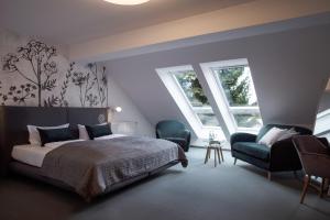 a bedroom with a bed and a chair and two windows at Hotel & Restaurant Am Alten Rhin in Neuruppin
