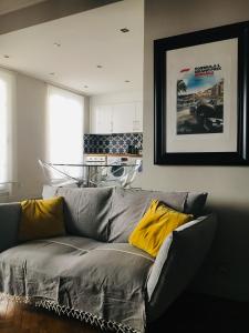 - un salon avec un canapé gris et des oreillers jaunes dans l'établissement Le petit bourgeois de Nice, à Nice