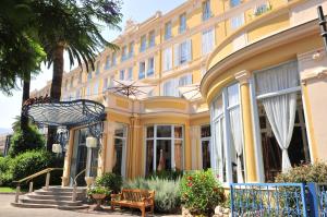a large yellow building with a bench in front of it at Hôtel Miléade L'Orangeraie - Menton in Menton