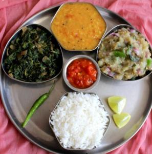 Namaskar Lodge and Homestay في غاواهاتي: طبق من الطعام مع الرز والخضار على الطاولة