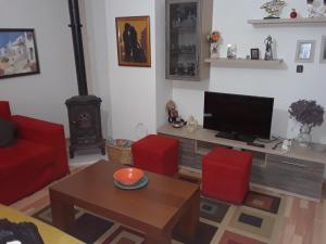 a living room with a television and red chairs at PERLES Apartament KORCE in Korçë