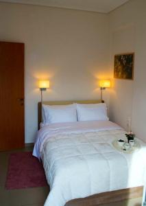 een slaapkamer met een groot wit bed met 2 lampen bij SUNNY CENTRAL LUXURY APARTMENT in Volos
