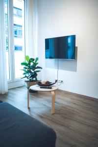 a living room with a table and a tv on a wall at Stylisch eingerichtete Wohnung mitten in München! in Munich