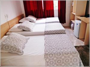 três camas individuais num quarto com cortinas vermelhas em Hotel Anjos LTDA em Gravataí