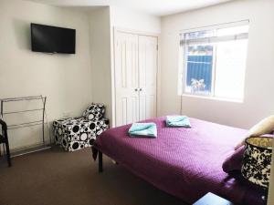 1 dormitorio con 1 cama, 1 silla y TV en Balcatta Sanctuary, en Perth
