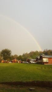 富特罗诺Turismo Jaos Cabañas Tinas y Quincho的天空中一根彩虹,在田野上