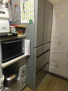 einen Kühlschrank aus Edelstahl mit einer Mikrowelle in der Küche in der Unterkunft Sunny house in Otaru