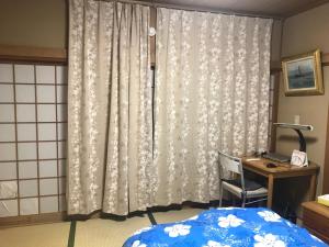 Schlafzimmer mit einem Bett, einem Schreibtisch und einem Vorhang in der Unterkunft Sunny house in Otaru