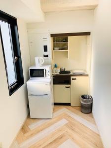 a small kitchen with a white refrigerator and a window at WELLSTAY Honmachi in Osaka