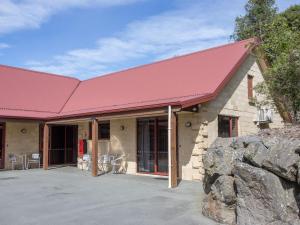 a building with a red roof with tables and chairs at ASURE Scenic Route Motor Lodge in Geraldine