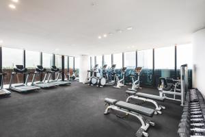 a gym with rows of treadmills and machines at Sky One Apartments by CLLIX in Box Hill