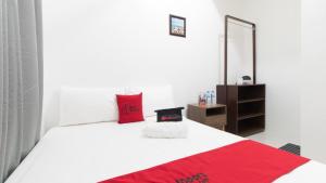 una camera da letto con un letto bianco con cuscini rossi e uno specchio di RedDoorz near Liceo De Cagayan University Highschool a Cagayan de Oro