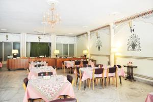 una sala da pranzo con tavoli, sedie e lampadario a braccio di Hotel Meghniwas a Jaipur