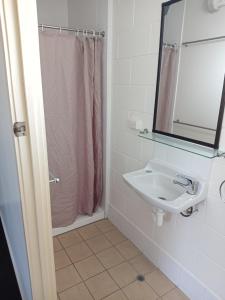 uma casa de banho branca com um lavatório e um espelho em Millmerran Motel em Millmerran