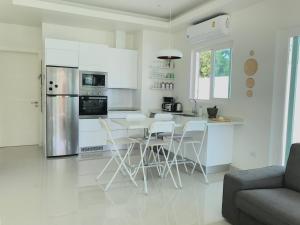 a kitchen with white cabinets and a table and chairs at My Orchid HuaHin in Hua Hin