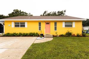 a yellow house with a red door on a yard at Manatee River Cottage in Historical OldTown, sleeps up to 7 people in Palmetto