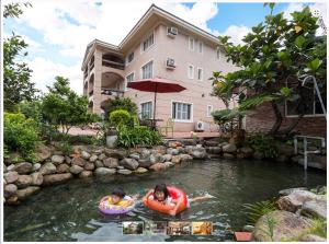 two people are swimming in a pond in a backyard at GuiZhuLin B&B in Jiaoxi