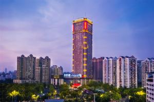 een hoog gebouw met lichten aan in een stad bij Haikou Mingguang Shengyi Hotel (Previous Mingguang International Hotel) in Haikou