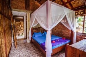 a bed in a room with a mosquito net at Garden Inn in Bukit Lawang