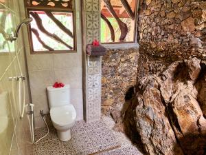 a bathroom with a toilet in a stone wall at Garden Inn in Bukit Lawang