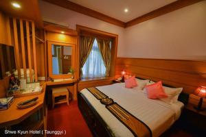a bedroom with a bed and a desk with a computer at Shwe Kyun Hotel in Taunggyi