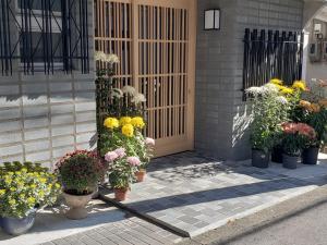 un montón de flores en macetas delante de una puerta en Shiroyama Ryokan, en Ikuma