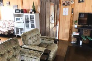 読谷村にあるSMILE ONE GUEST HOUSE OKINAWAのリビングルーム(ソファ、椅子、テレビ付)