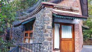 un pequeño edificio de ladrillo con puerta de madera en Wildernest en Thekkadi