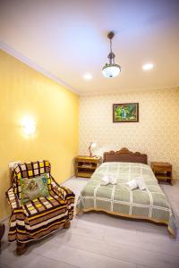 1 dormitorio con 1 cama y 1 silla en Guest House Happy Holidays, en Tiflis