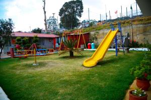 a playground with a yellow slide in a yard at Paradise Perfect in Ooty