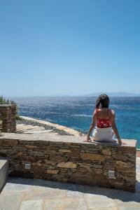Agios RomanosにあるArchipelagotinosの石垣に座って海を眺める女
