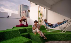 a group of people sitting on hammocks on the grass at ST Signature Chinatown in Singapore