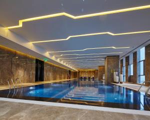 een groot zwembad in een gebouw met een plafond bij Wanda Realm Hotel Dongying in Dongying