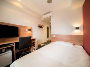a hotel room with two beds and a flat screen tv at Super Hotel Nagoya Ekimae in Nagoya