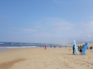 a group of people standing on a beach with surfboards at Blue Ocean in Moliets-et-Maa
